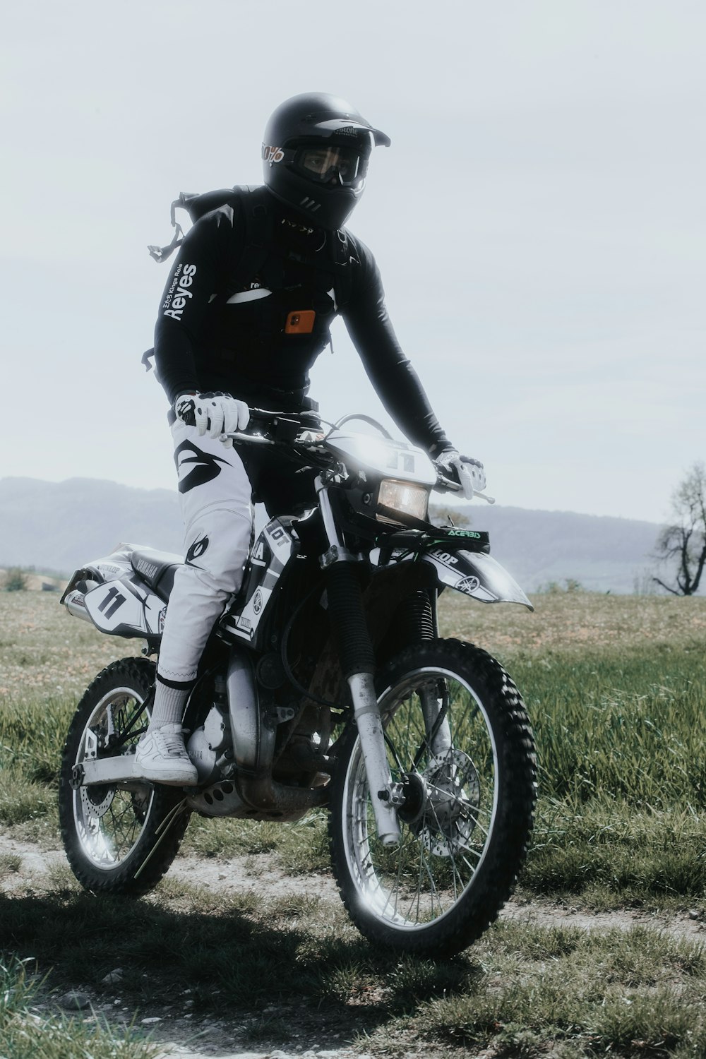 motocicleta blanca y negra en el campo de hierba verde durante el día