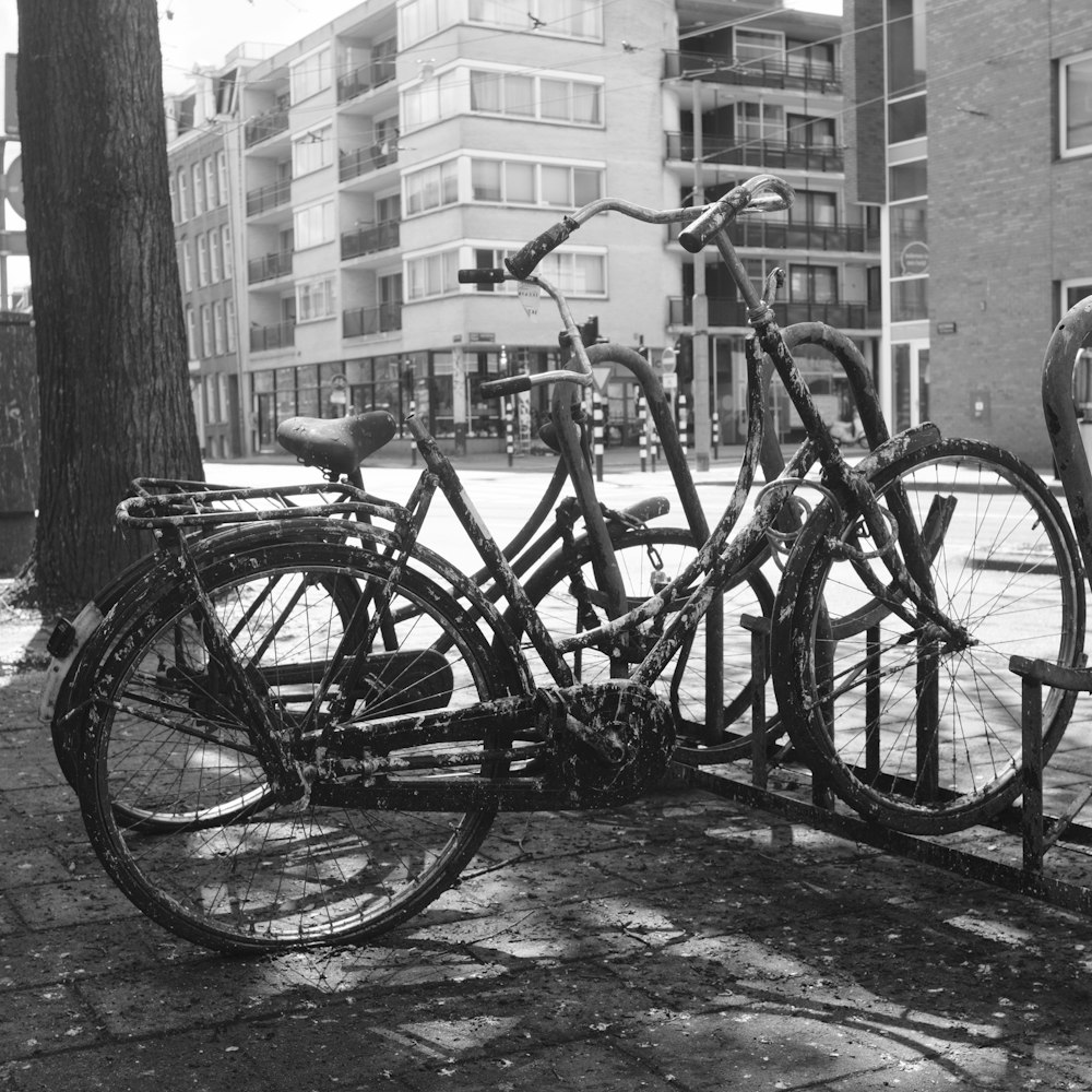 grayscale photo of city bikes parked beside concrete building