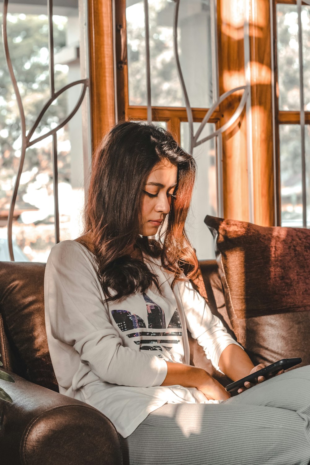 woman in white long sleeve shirt sitting on brown chair