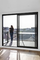 woman in blue denim jeans standing near glass window during daytime