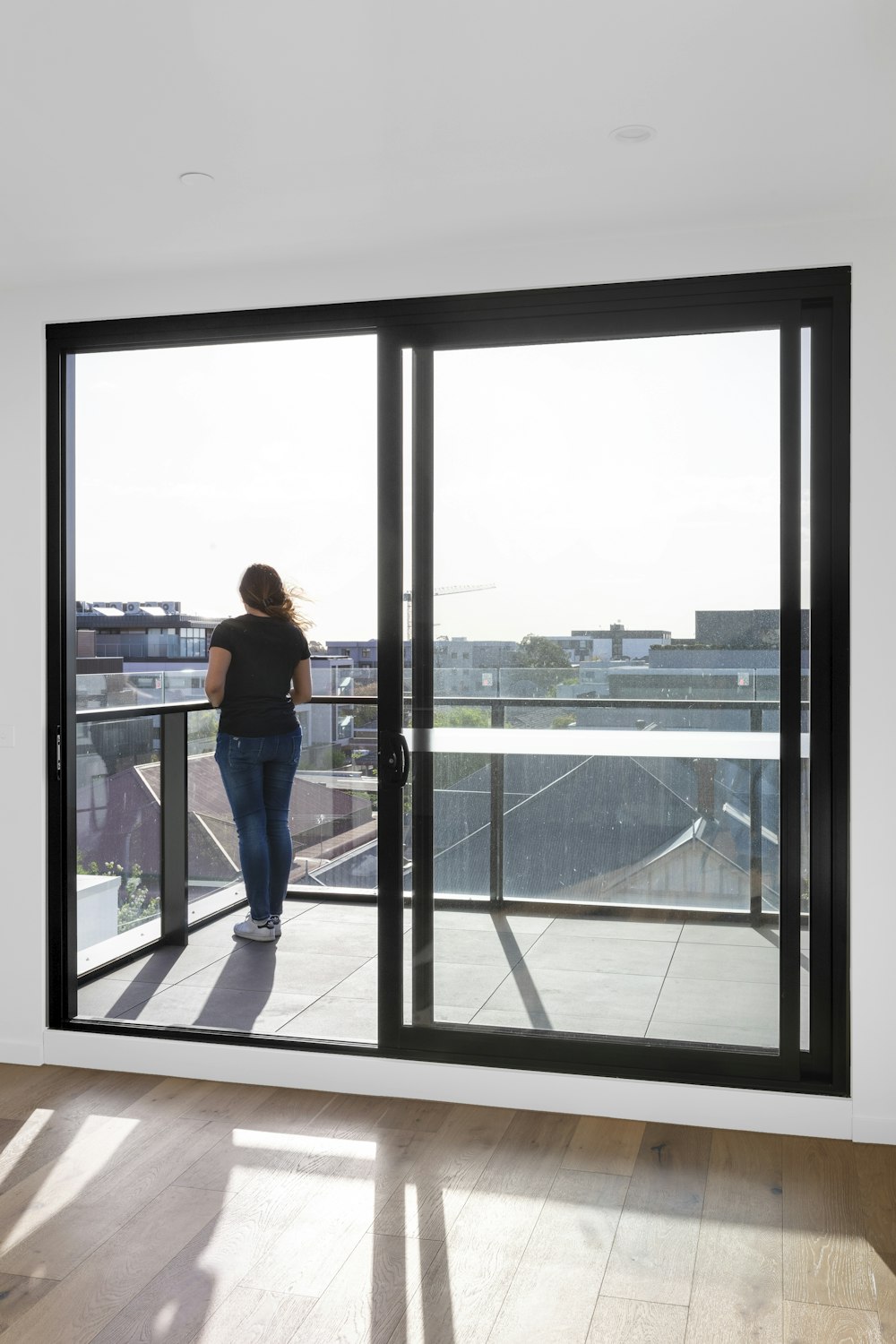 Mujer en jeans de mezclilla azul de pie cerca de la ventana de vidrio durante el día