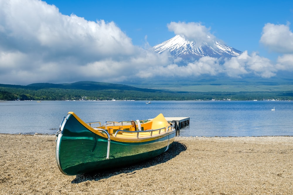 green and yellow boat on beach shore during daytime