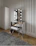 A bright, airy bathroom corner featuring a stylish lustranest vanity stool beside a decorative mirror.