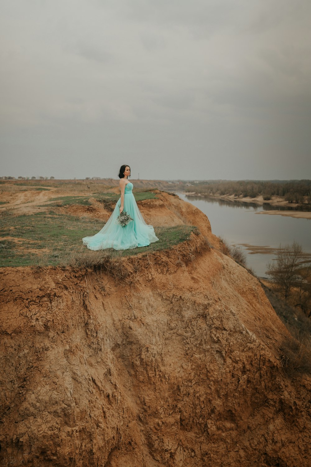woman in white wedding dress standing on brown field near lake during daytime