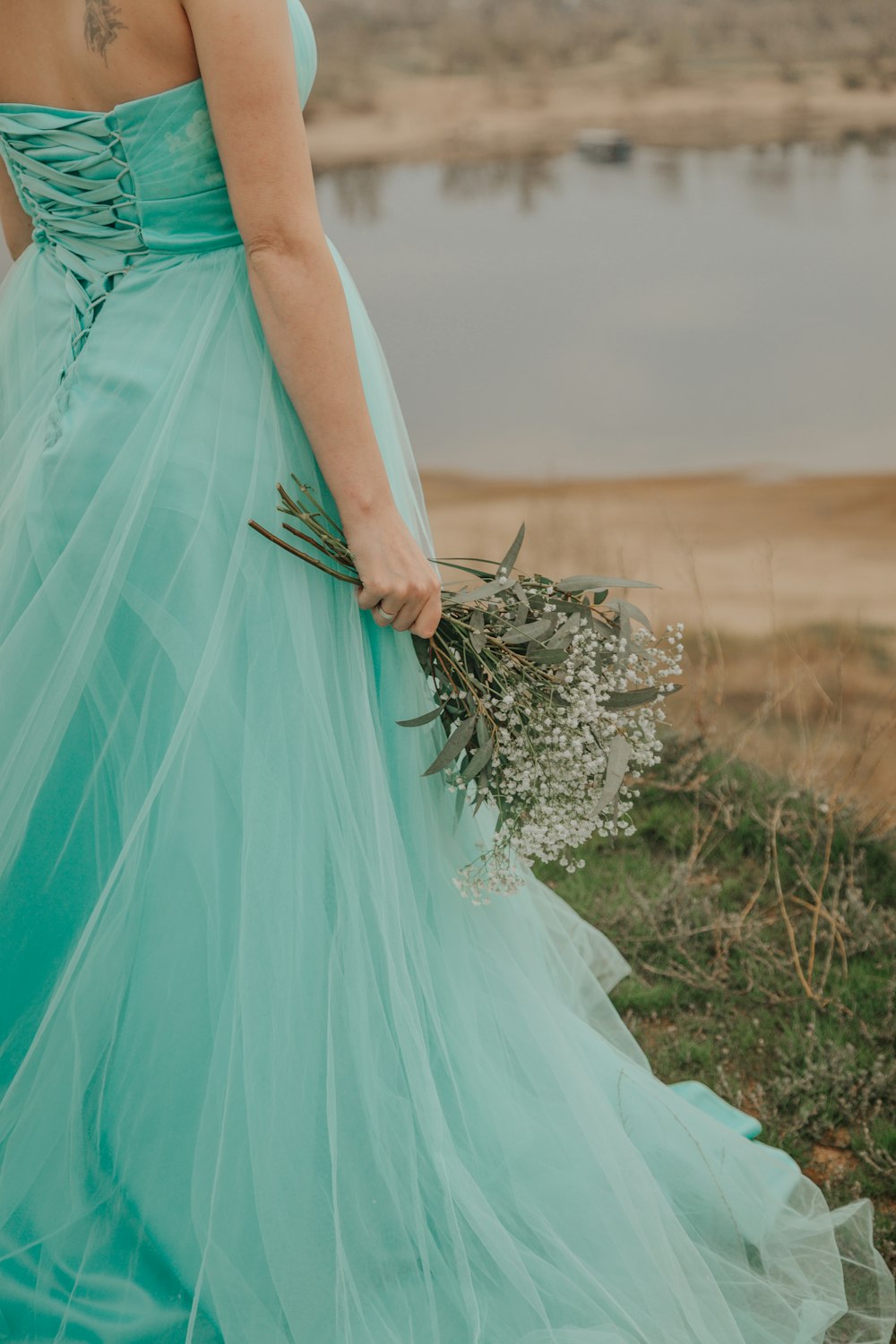 woman in blue sleeveless dress holding bouquet of flowers