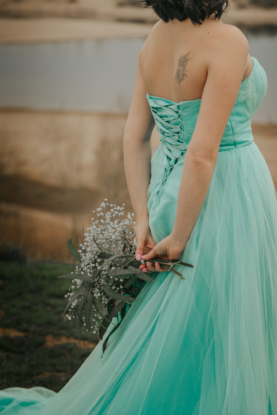 woman in teal tube dress holding white flowers