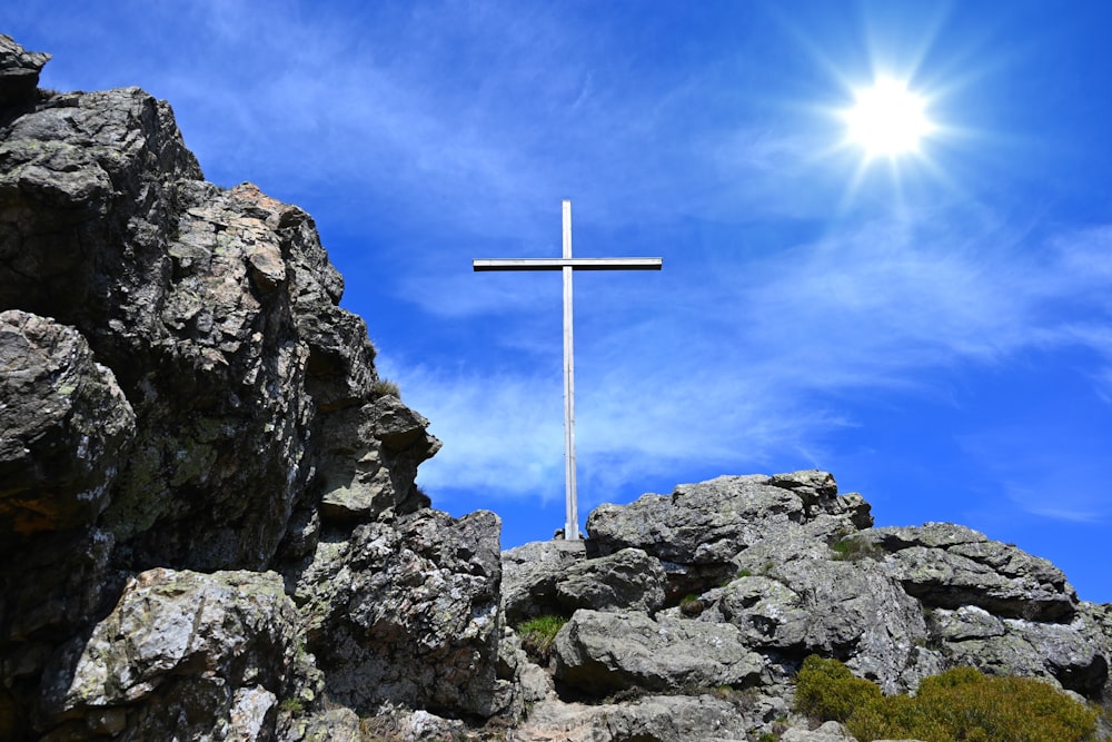 cross on rocky mountain under blue sky during daytime
