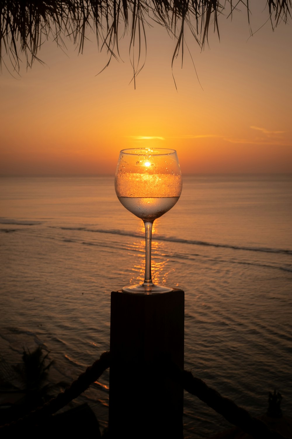 Bicchiere di vino trasparente sul tavolo di legno marrone durante il tramonto