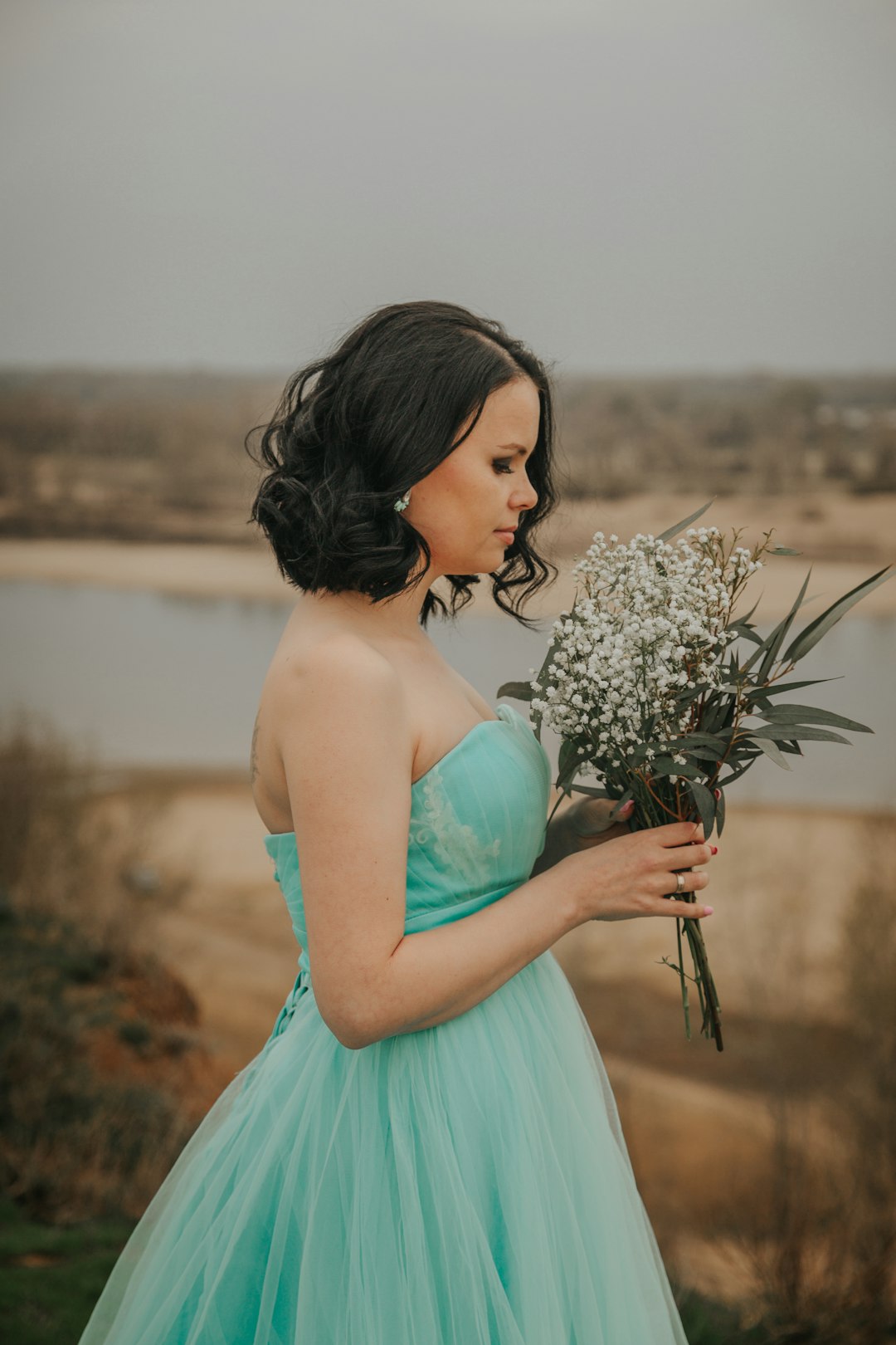 woman in teal tube dress holding bouquet of flowers