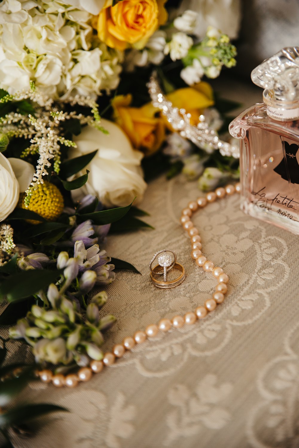 gold and silver beaded necklace beside perfume bottle