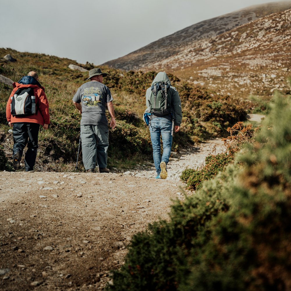 2 men walking on brown dirt road during daytime