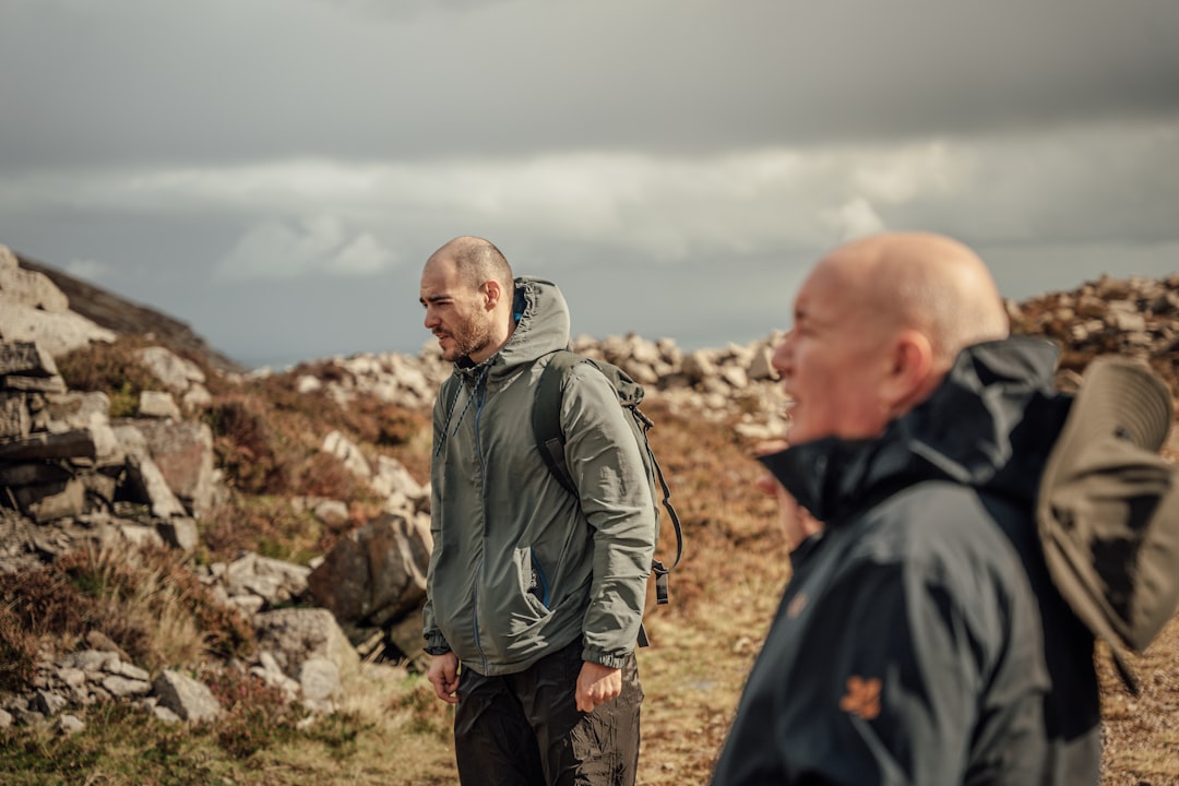 man in gray jacket standing on brown rock during daytime