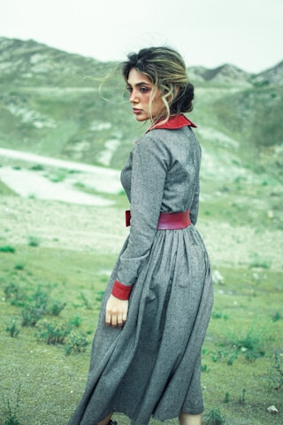 woman in black long sleeve dress standing on green grass field during daytime