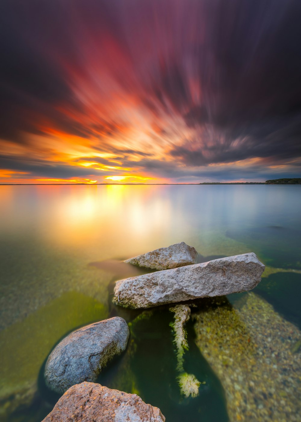 gray rock on body of water during sunset