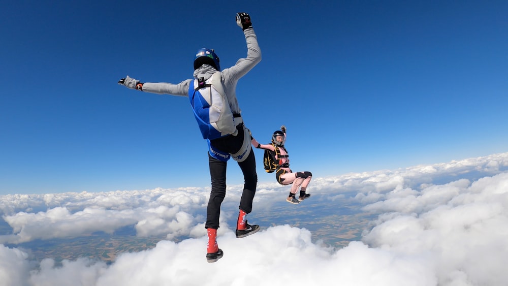 man in white and blue jacket and blue pants jumping on mid air under blue sky