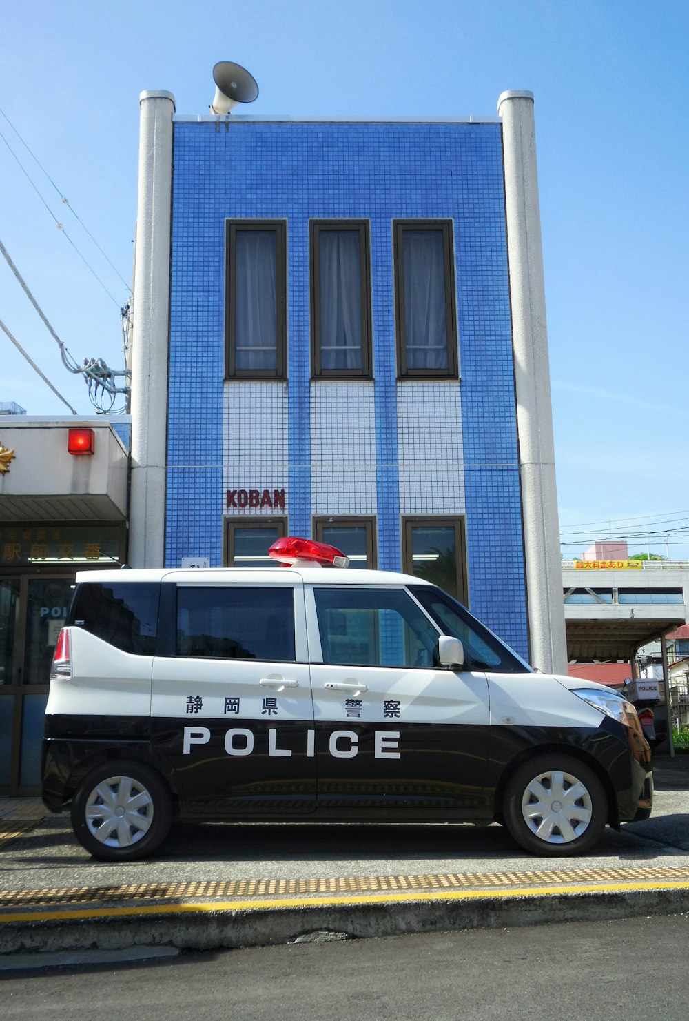 white and black police car in front of blue building