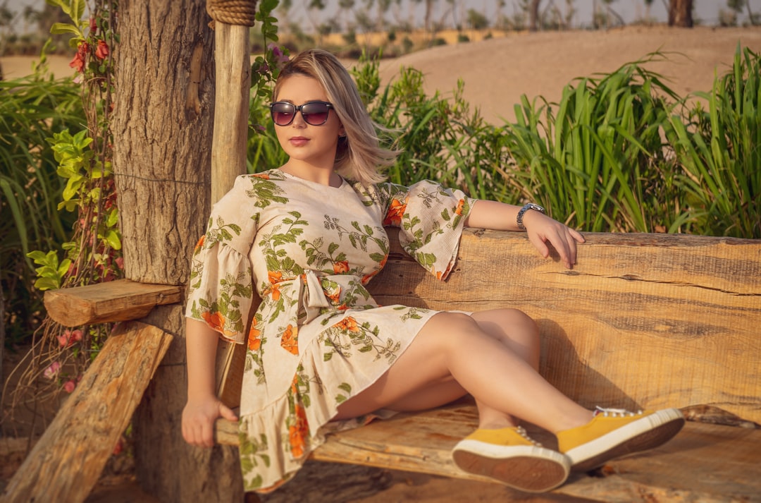 woman in white and red floral dress sitting on brown wooden bench