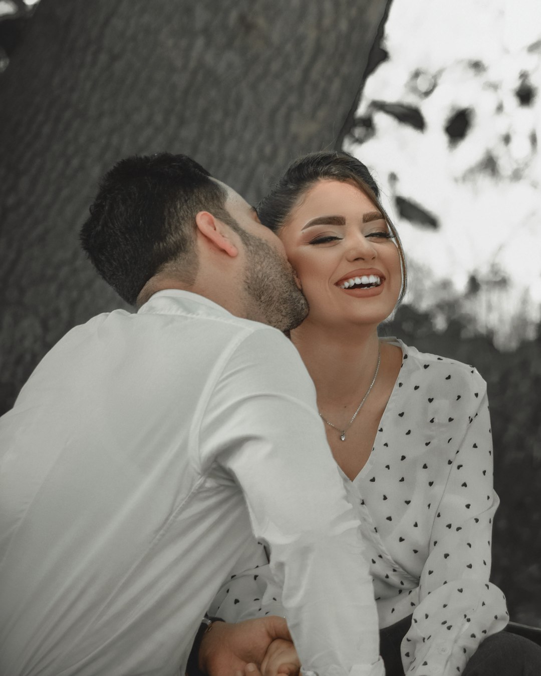 man in white dress shirt hugging woman in white and black polka dot dress