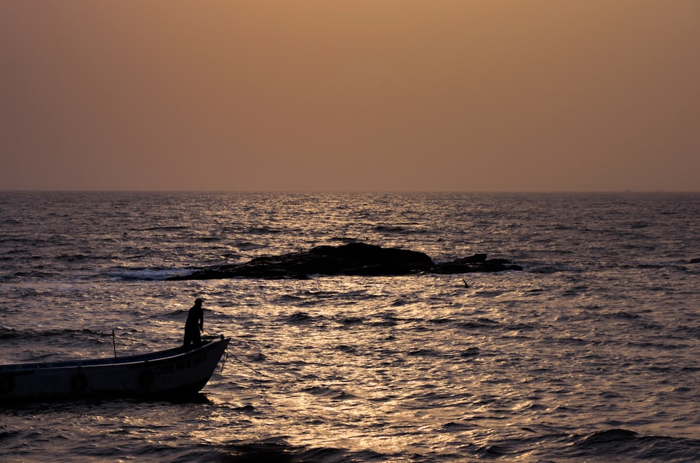 silhouette of boat on sea during sunset