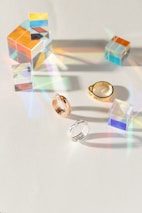 A modern display of prismatisch jewellery pieces arranged on a crisp white surface with vibrant light reflections.