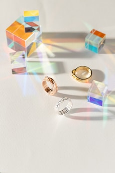 A modern display of prismatisch jewellery pieces arranged on a crisp white surface with vibrant light reflections.