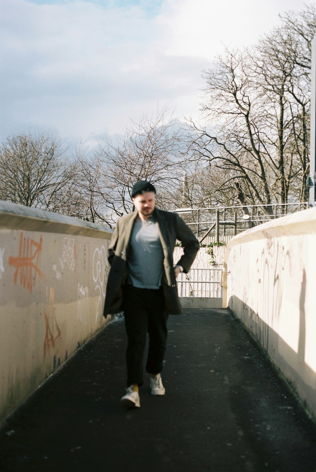 man in gray jacket standing beside white wall during daytime