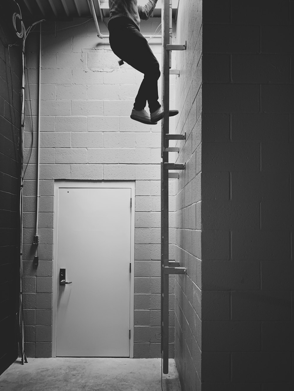 person in black pants and black shoes jumping on a white wall