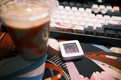 A compact cooling fan on a desk beside a laptop and a cup of coffee.