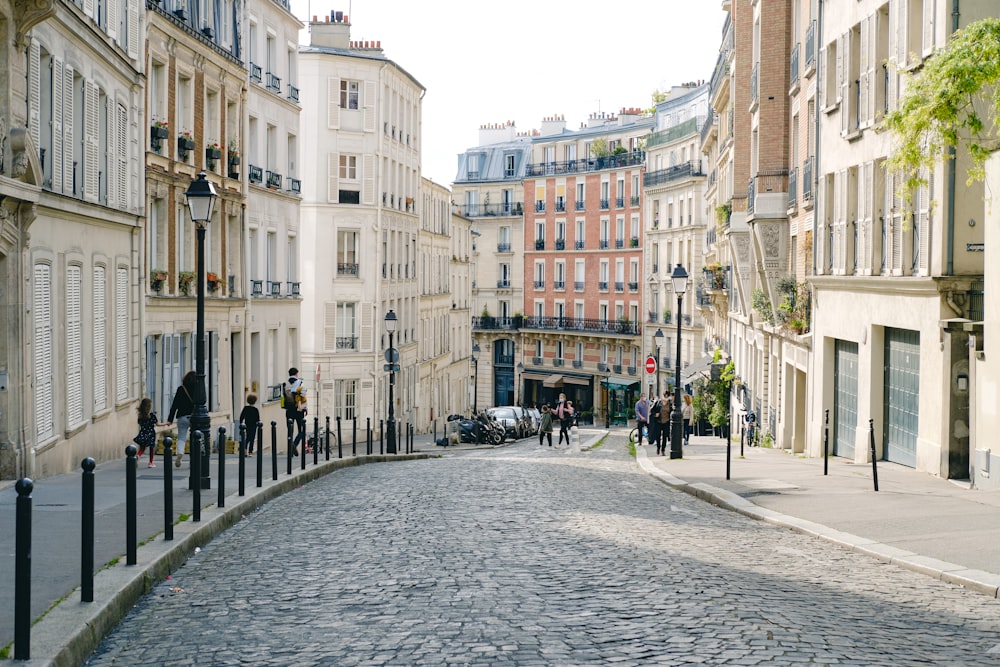 les gens marchent dans la rue entre les bâtiments pendant la journée