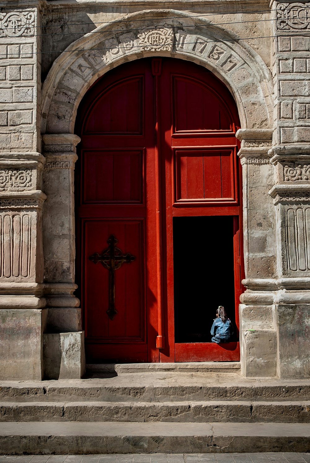 2 women in blue dress standing in front of red wooden door