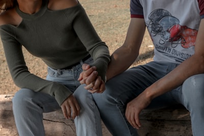 Happy couple sitting on a park bench, both wearing matching faith-themed sweatshirts.