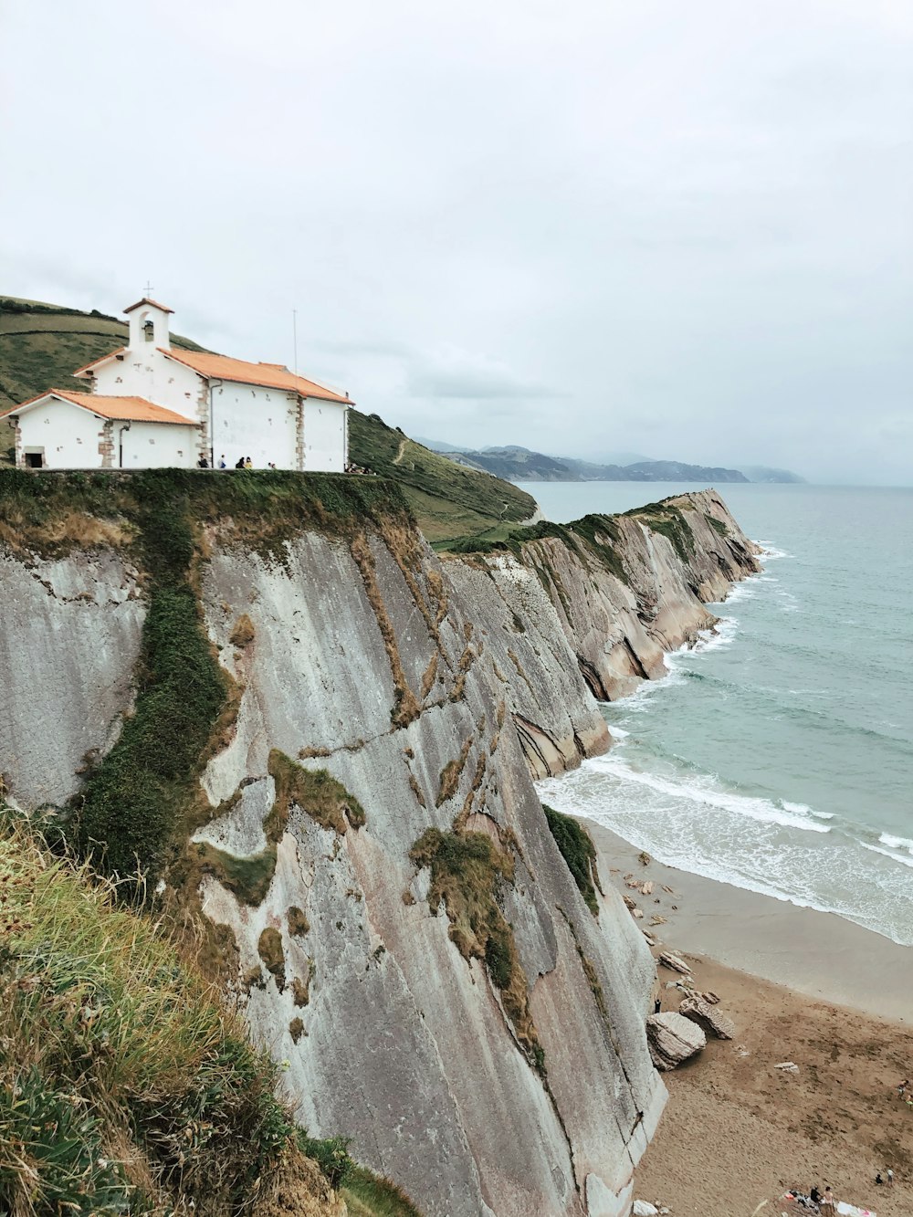 a white house sitting on top of a cliff next to the ocean