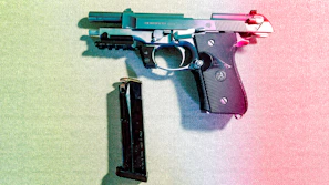 A dynamic shot of a handgun with a vibrant #f96302 accent, placed on a dark textured surface to emphasize its design.