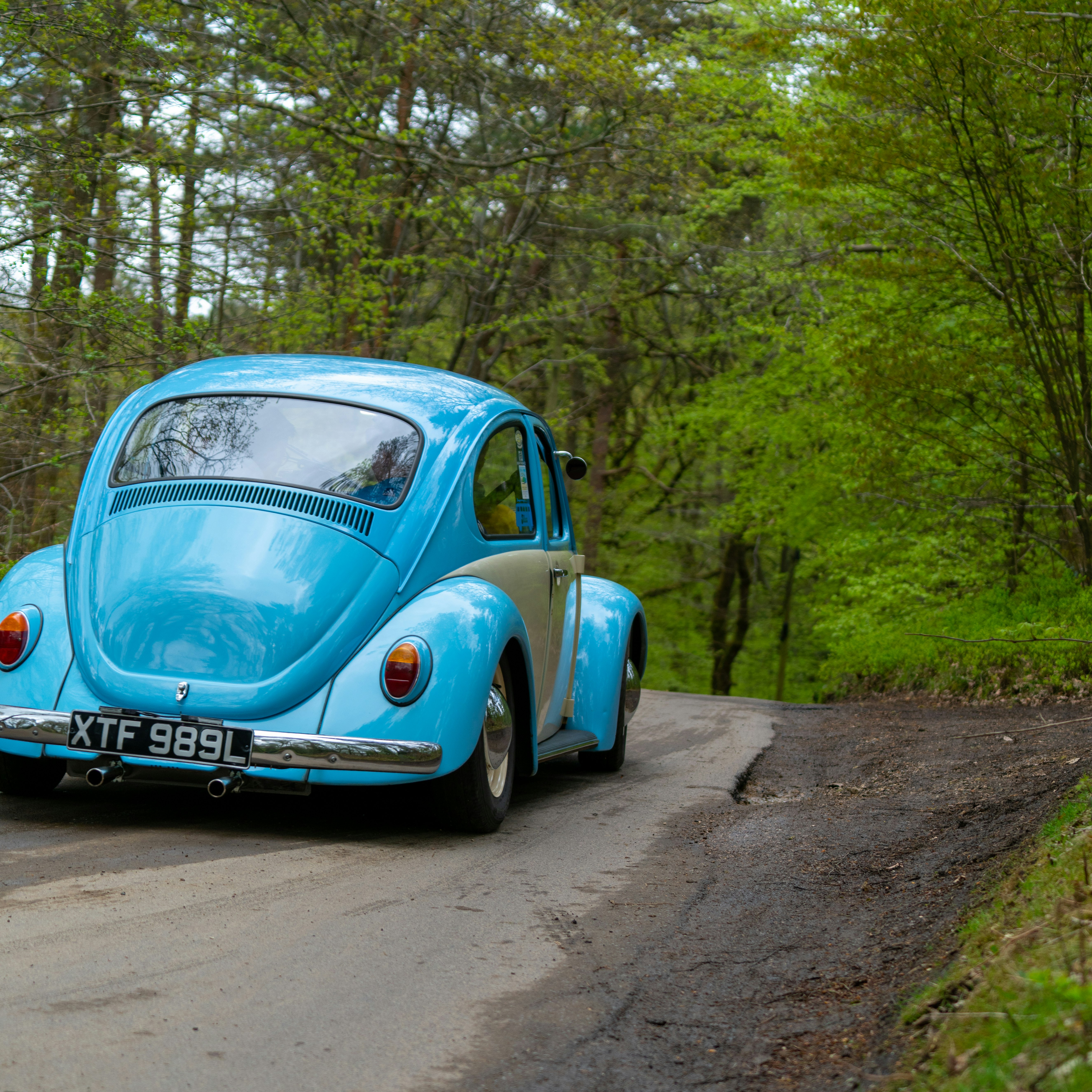 blue volkswagen beetle parked on dirt road during daytime