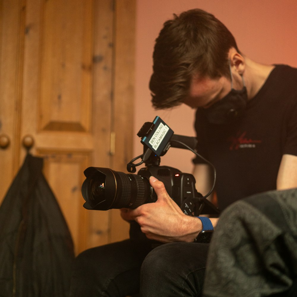 man in black crew neck t-shirt holding black dslr camera