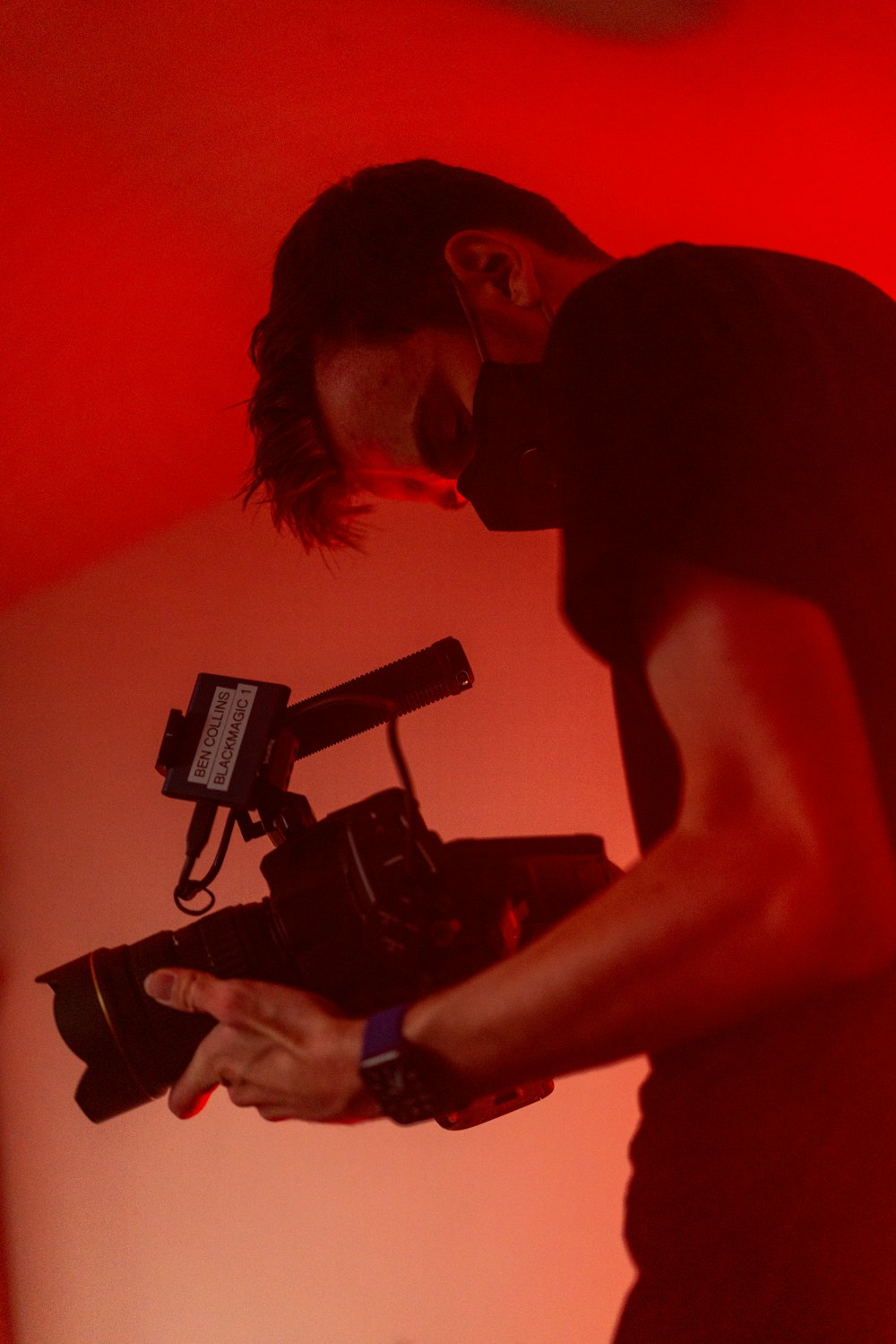 man in black tank top holding black video camera