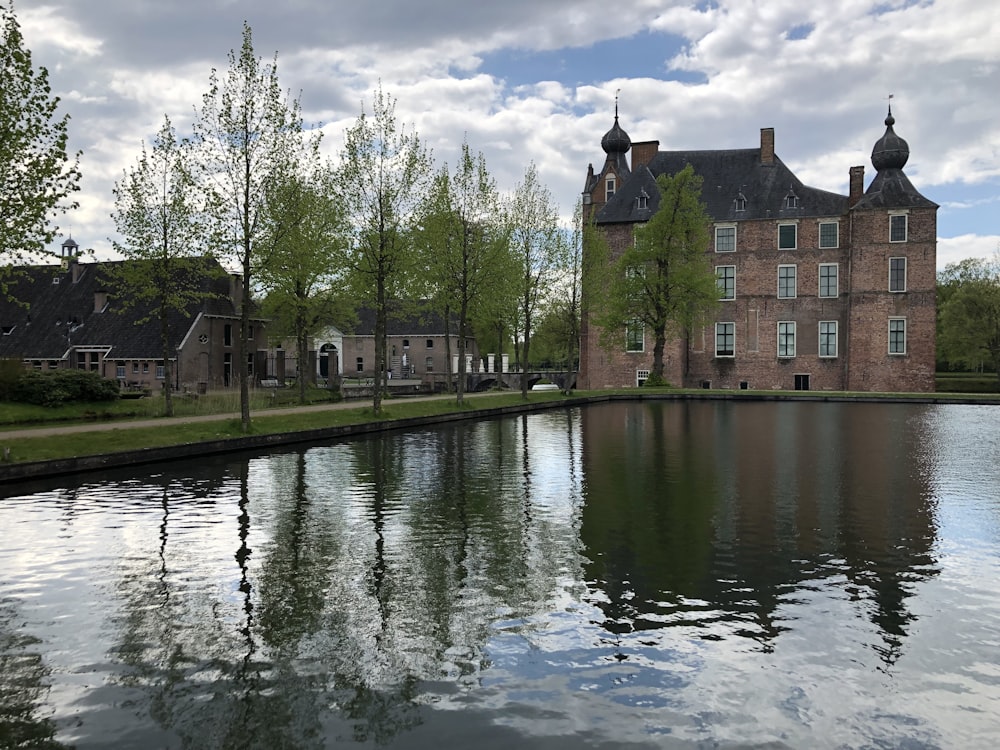 brown concrete building near green trees and river during daytime