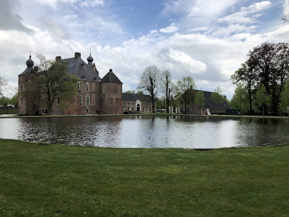 brown concrete building near green grass field and body of water under white clouds and blue