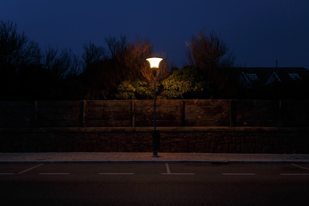 white light post near brown wooden fence during night time