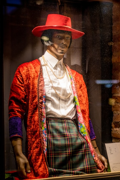 A sharp, modern men's outfit displayed on a mannequin against a bold red background.