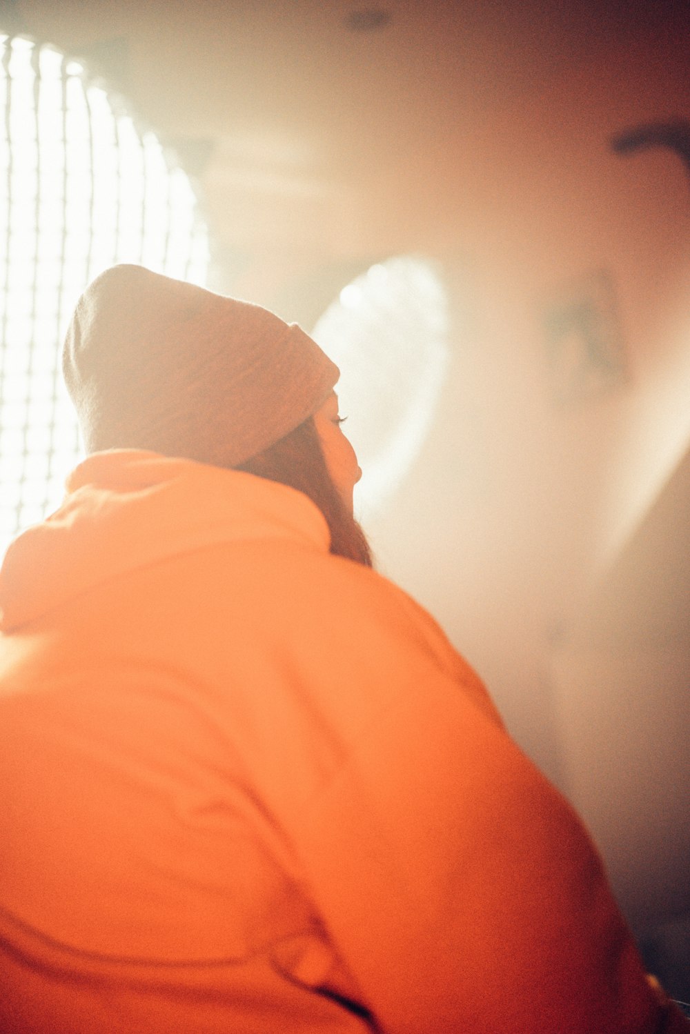 person in orange shirt wearing white knit cap