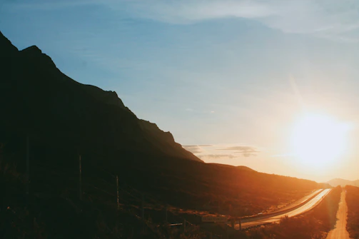 A candid photo of a winding mountain road bathed in golden sunset light, capturing the essence of adventure.