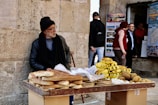 man in black jacket standing beside yellow banana fruit