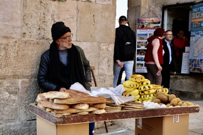 man in black jacket standing beside yellow banana fruit