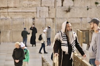 A group gathered around a guide sharing tales beside a historic stone wall.