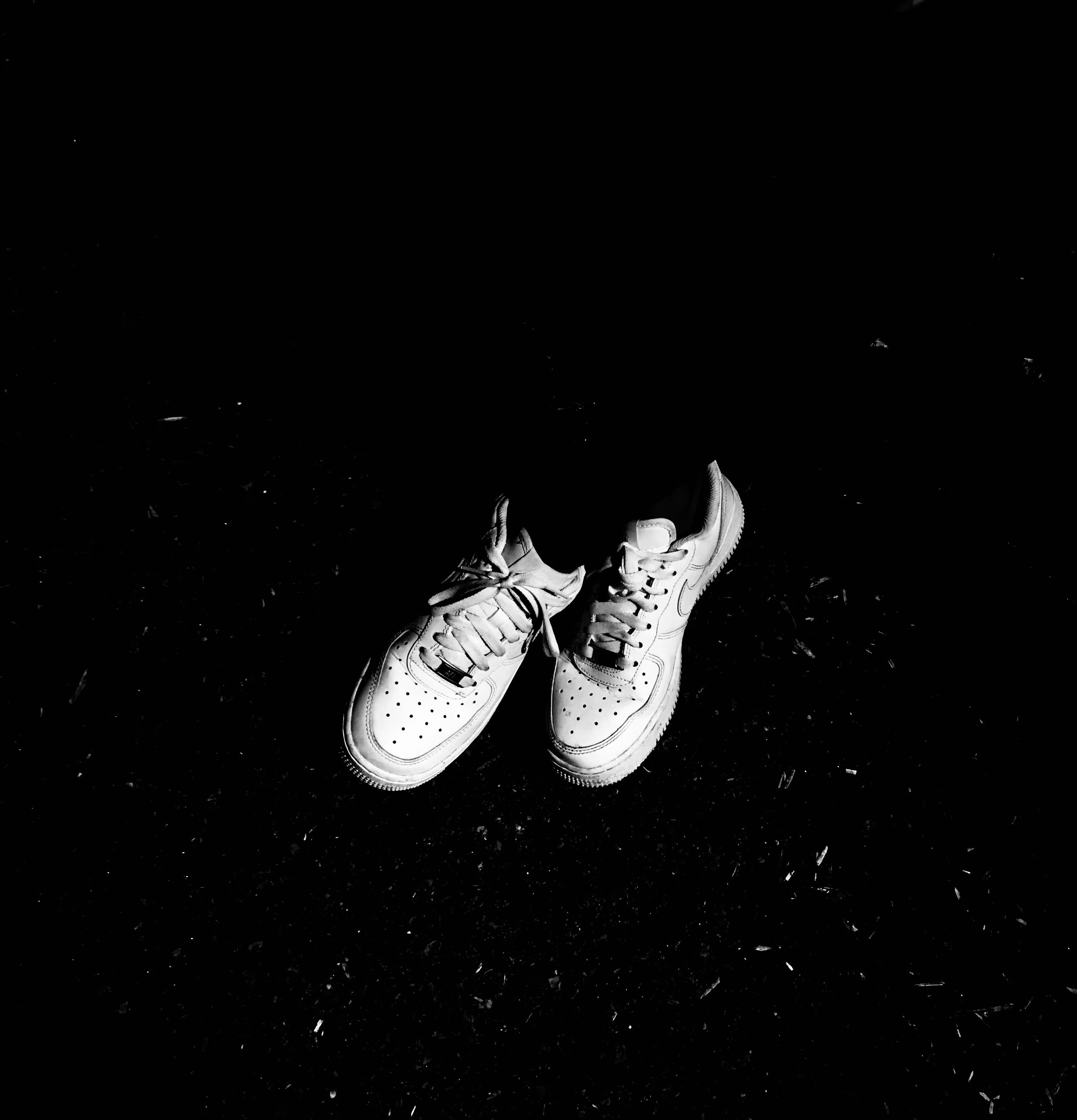 Sneaker pair displayed on dark background with dramatic side lighting