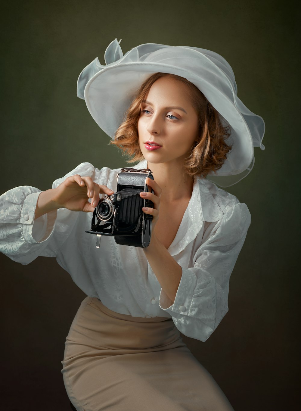 Femme en chemise à manches longues blanche tenant un appareil photo noir et argenté