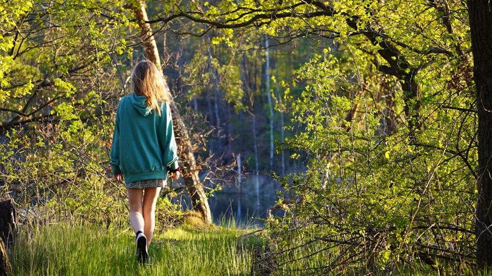 woman in green long sleeve shirt and black pants standing on green grass field near body