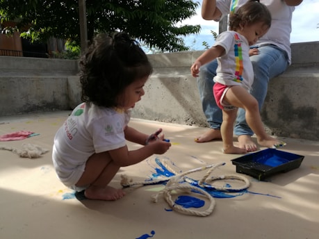 girl in white t-shirt sitting on sand during daytime