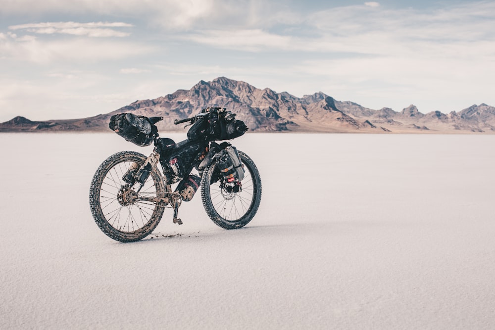 mountain bike nera su sabbia bianca vicino allo specchio d'acqua durante il giorno